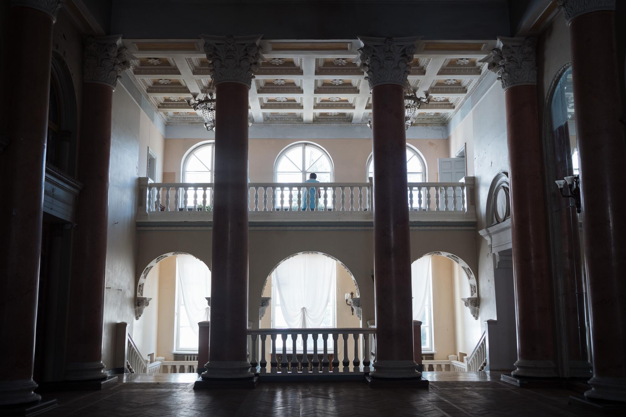 Inside of a grand building with arched windows and thick columns 