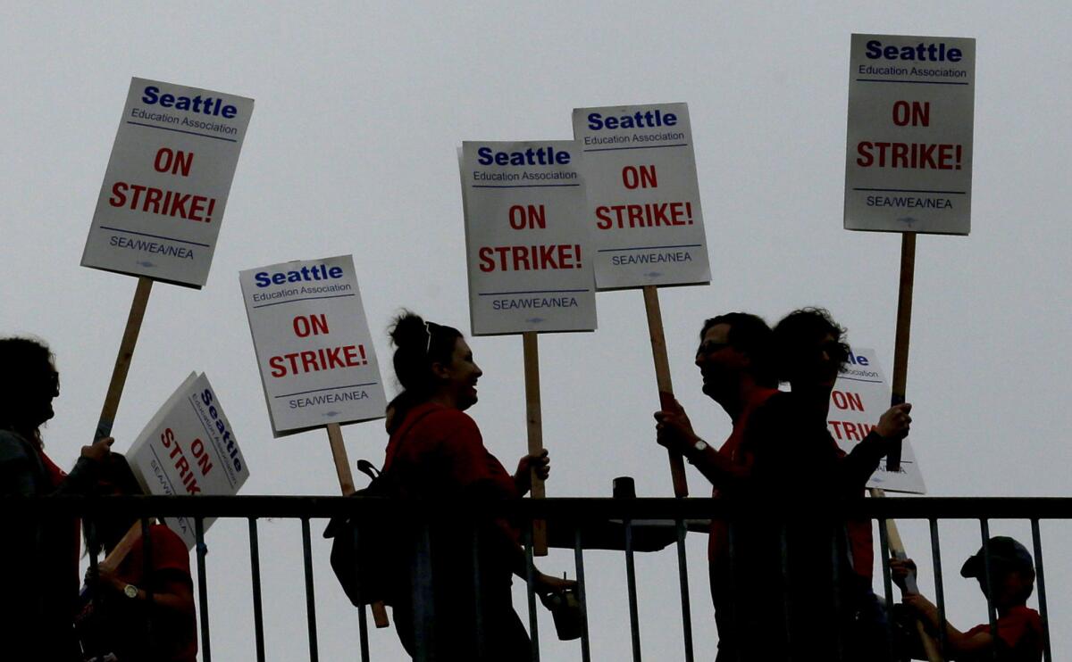 In this file photo from Sept. 10, striking Seattle School District teachers and other educators walk a picket line on a pedestrian overpass near Franklin High School in Seattle.