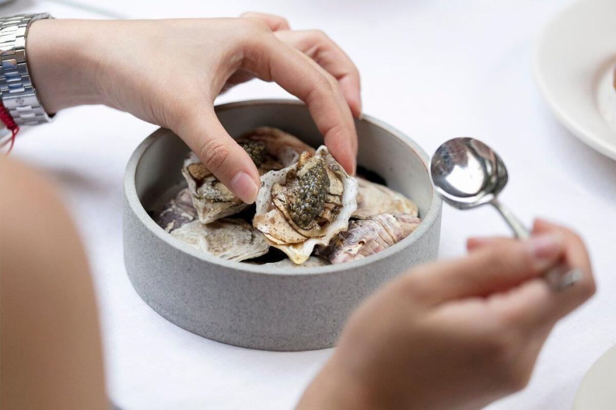 A diner dives into her course of Kusshi oysters with porcini mushrooms and caviar.