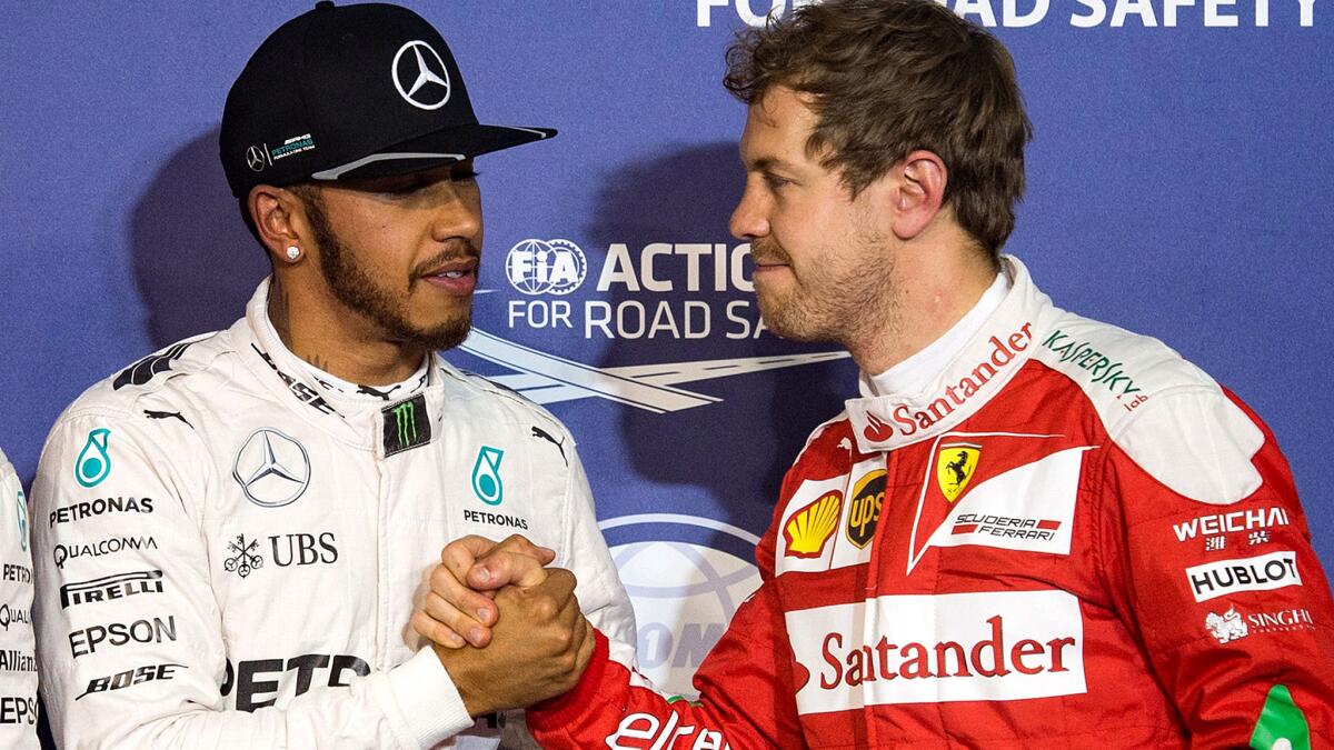 Formula One driver Lewis Hamilton, left, is congratulated by rival Sebastian Vettel on Saturday after securing the pole position for the Bahrain Grand Prix.
