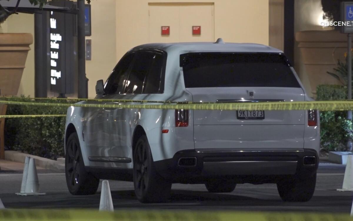 A Rolls-Royce SVU is surrounded by police tape in a dark parking lot