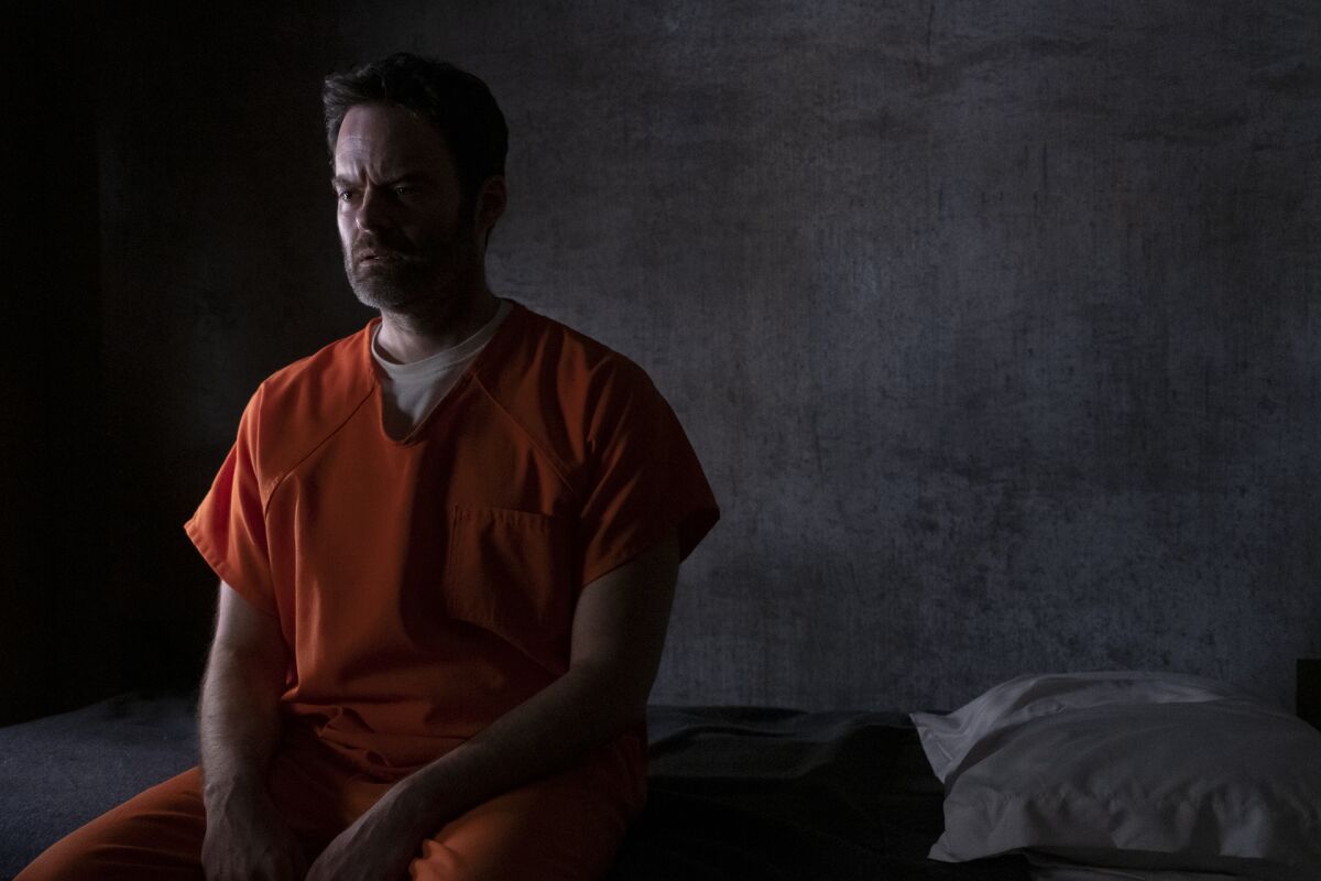 A killer (Barry, played by Bill Hader) in an orange jumpsuit sits in his dark prison cell in "Barry."