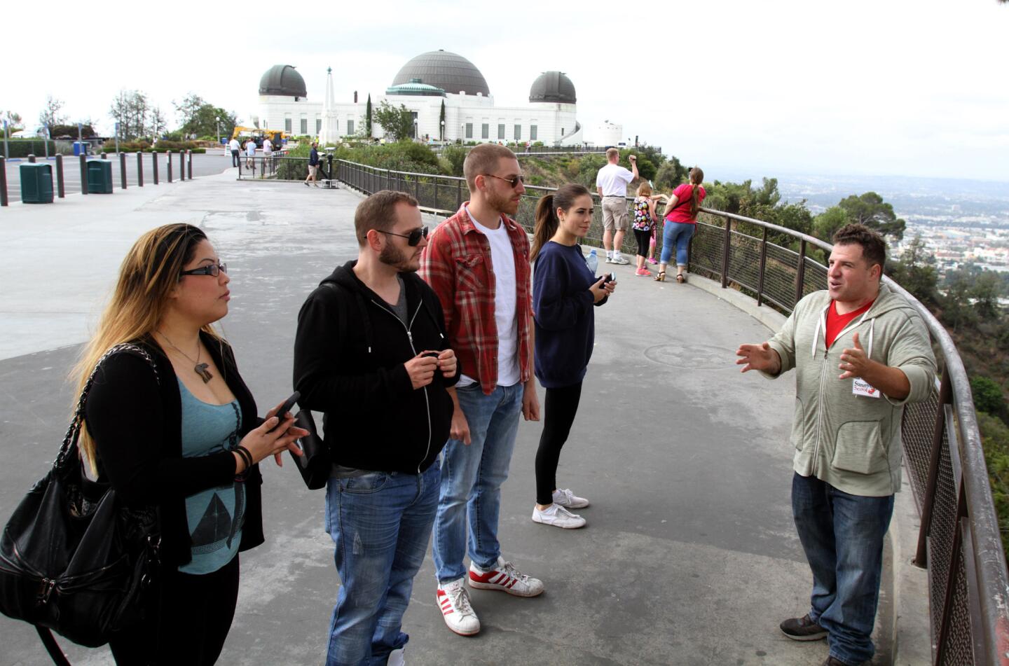 Company co-owner Michael Hunter, right, talks about the history of the Hollywood sign and the Griffith Observatory during a three-hour, Red Carpet tour offered by Burbank-based Sunnyday Scoot on Friday, June 5, 2015.