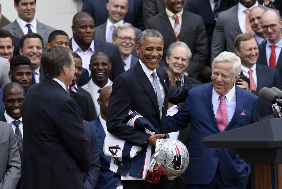 President Obama holds a signed New England Patriots football helmet and a jersey as he stands with team owner Robert Kraft, right, and Coach Bill Belichick on the South Lawn of the White House on Thursday.