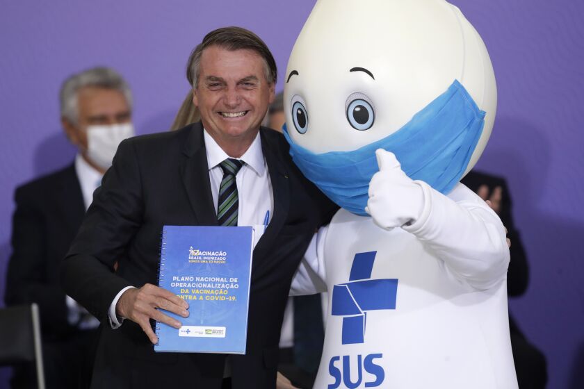 FILE - In this Dec. 16, 2020 file photo, BrazilIan President Jair Bolsonaro poses for photos with the mascot of the nation's vaccination campaign, named "Ze Gotinha," or Joseph Droplet, during a ceremony to present Brazil's National Vaccination Plan Against COVID-19, at Planalto presidential palace in Brasilia, Brazil. The Brazilian internet spent the last few days wondering about his apparent disappearance after Brazil's former President Lula joked that he may have been shoved aside due to political motivations. (AP Photo/Eraldo Peres, File)