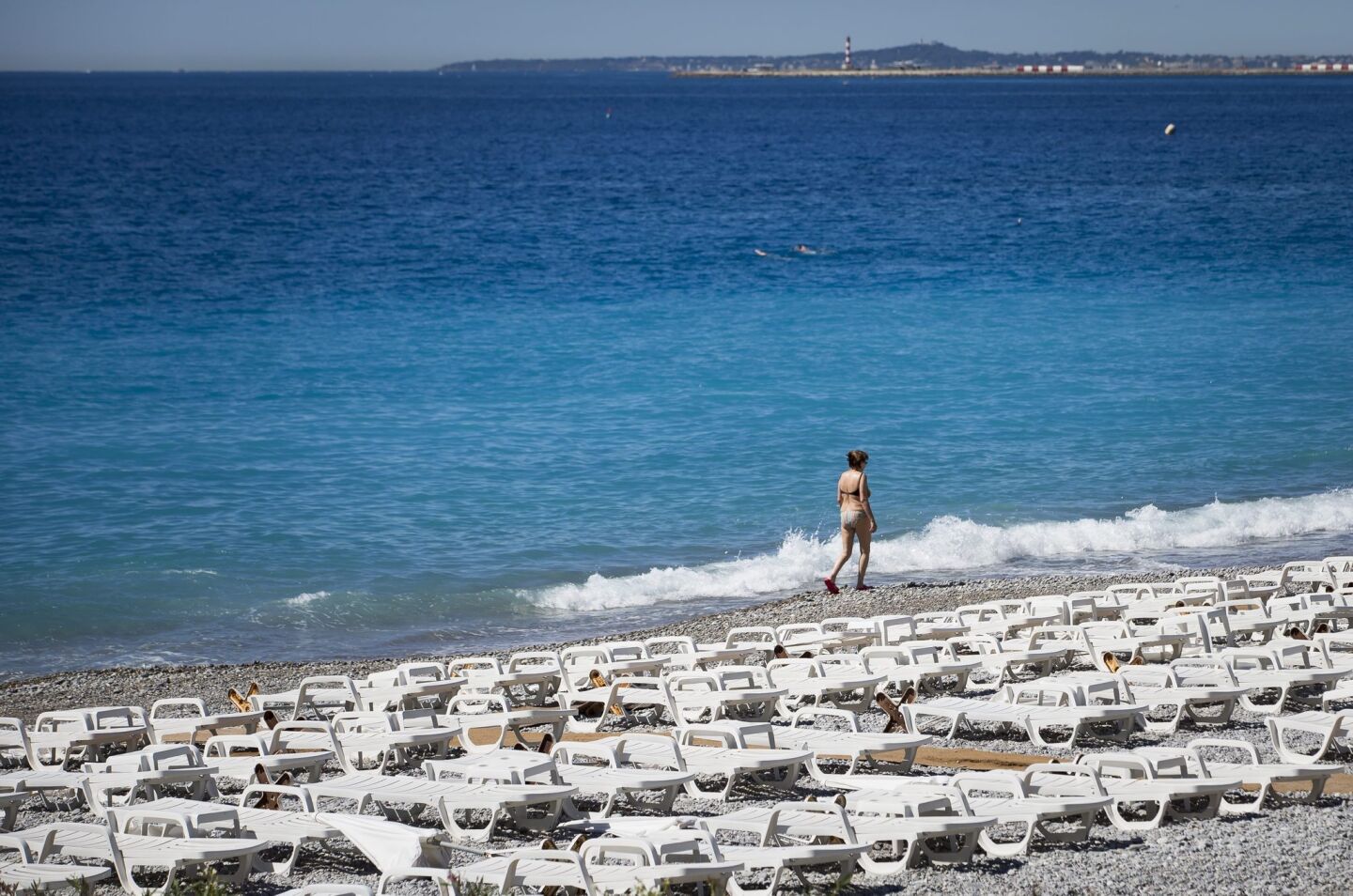 A woman walks alone on a deserted beach beside the Promenade des Anglais on July 6, 2016, in Nice, where the truck crashed into the crowd during the Bastille Day celebrations.