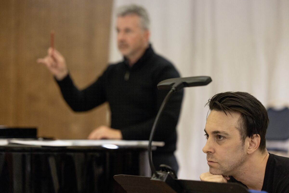 With Conductor Bruce Stasyna in the background, Director and co-librettist, John de los Santos watches during a rehearsal.