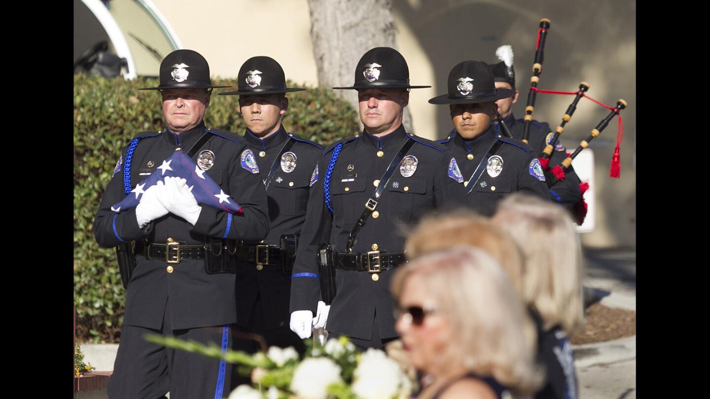 Members of the Laguna Beach Police honor guard, including Sgt. Dave McGill, holding the flag, and Cpl. Jason Ferris, center, march in unison during a remembrance ceremony Wednesday in honor of fallen Officer Jon Coutchie, who died in the line of duty in 2013.