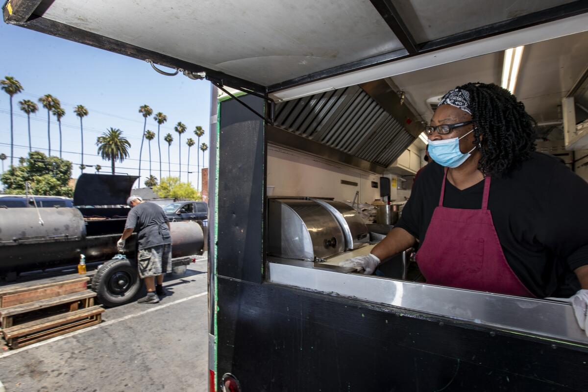 Regina Edwards stands inside the trailer as Lonnie Edwards mans the smoker at their RibTown BBQ.