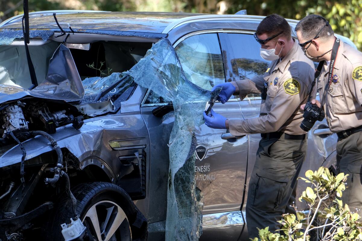Law enforcement officers look over the SUV Tiger Woods crashed in Rolling Hills Estates.