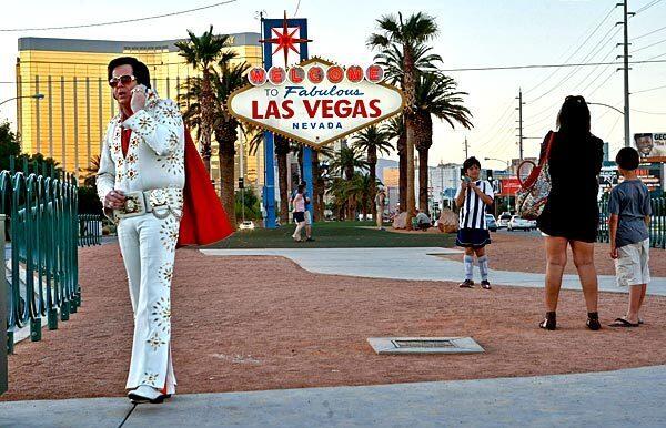 Elvis Presley impersonator Tim Ritchey takes a break while working for tips posing with people in front of the sign welcoming people to Las Vegas.