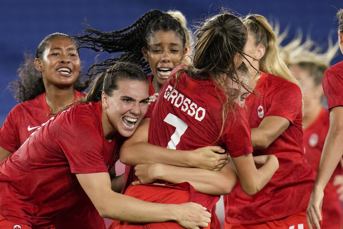Ecstatic teammates embrace Canada's Julia Grosso after she scored the winning goal against Sweden.