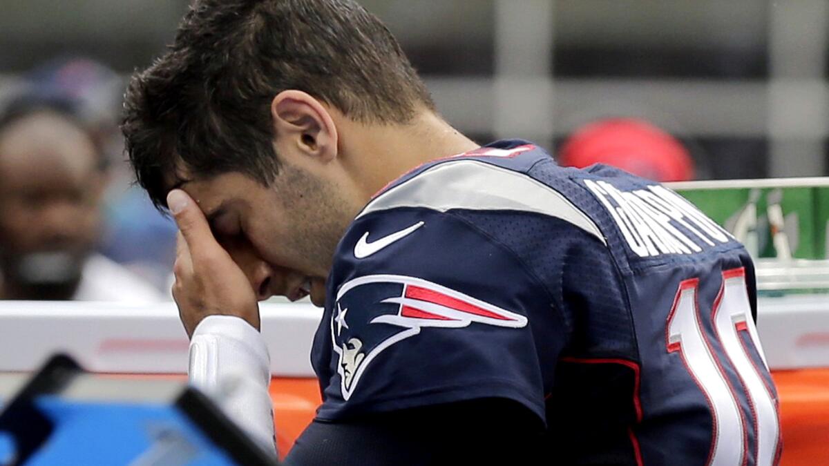 Patriots quarterback Jimmy Garoppolo tries to gather himself on the sideline after sustaining a shoulder injury that knocked him from Sunday's game.