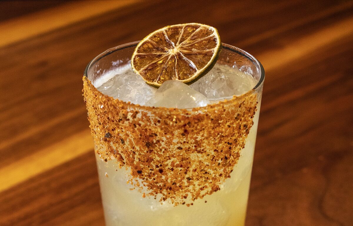 A margarita with a rim of Tajin, topped with a dried citrus slice