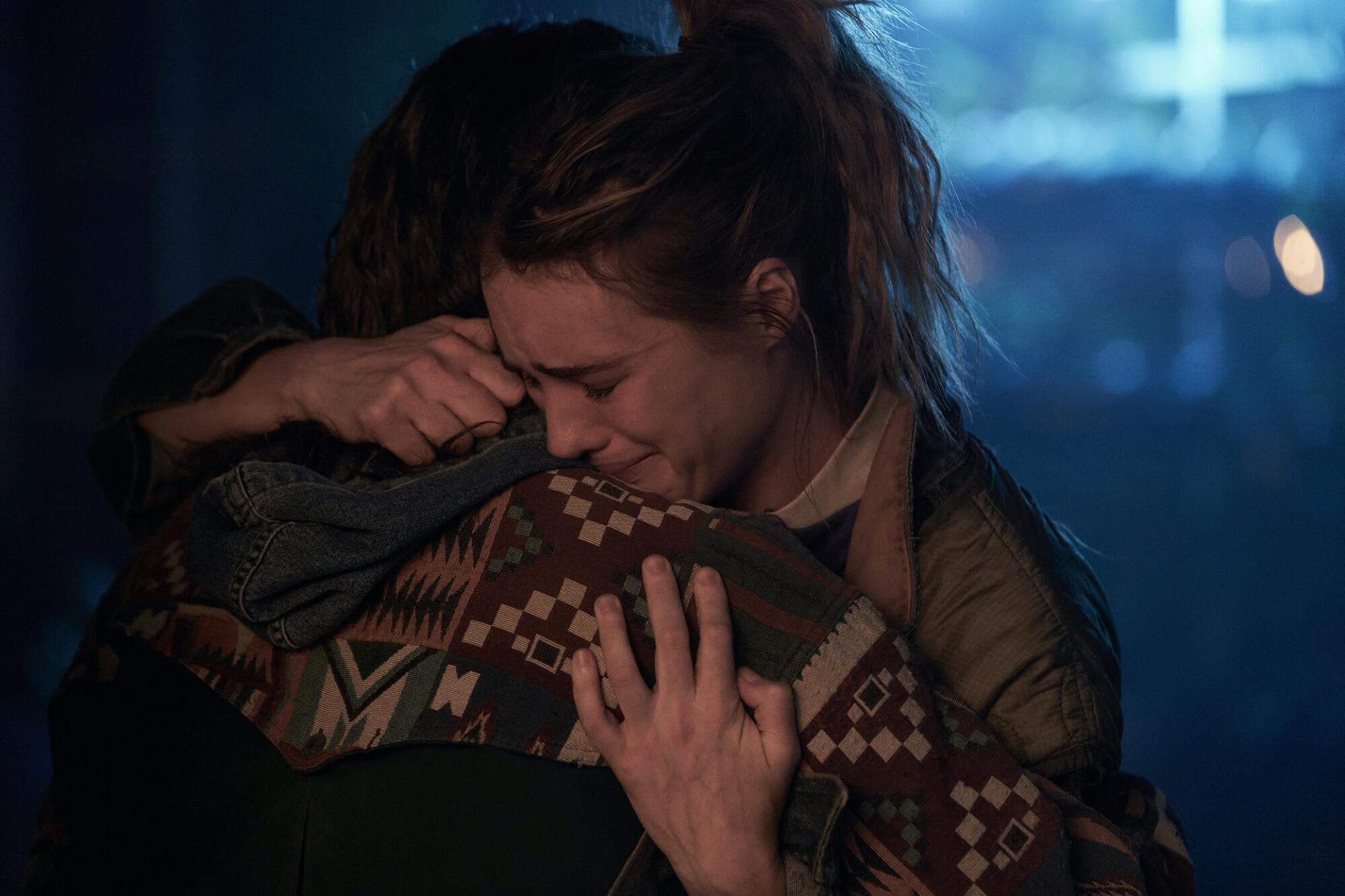 A woman cries on the shoulder of a man as they embrace.
