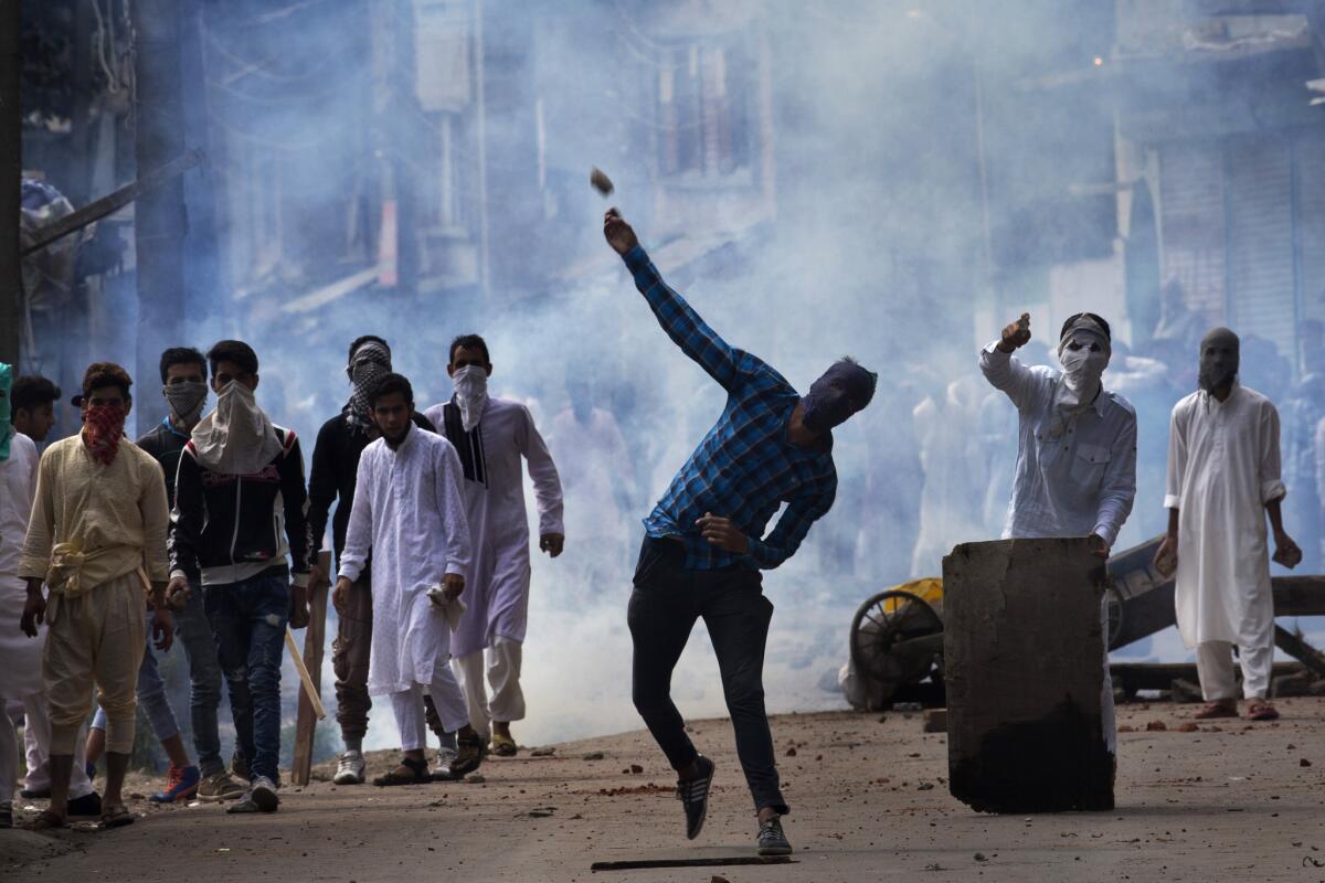 A Kashmiri throws a rock at Indian security personnel during a protest after Eid al-Adha prayers Tuesday in Srinagar, Indian-controlled Kashmir.