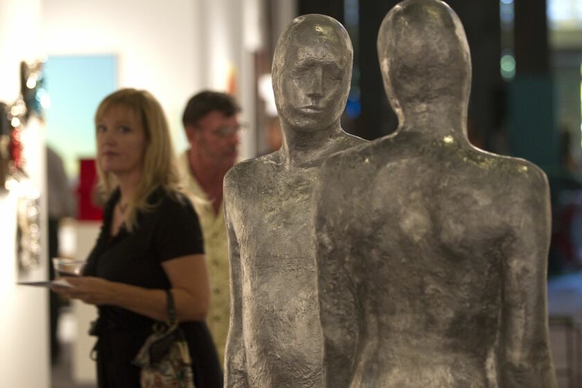 People attending the Art Fair walk past the sculpture "Counterparts" by artist Steinunn Thorarinsdottir..
