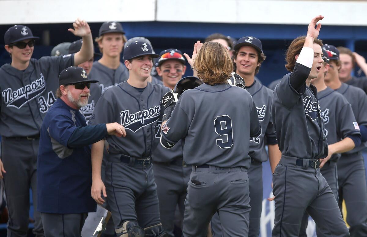 Newport Harbor High's John Olmstead (9) is congratulated at the dugout after he hit a two-run homer in a Sunset Conference crossover game at Fountain Valley on Friday.