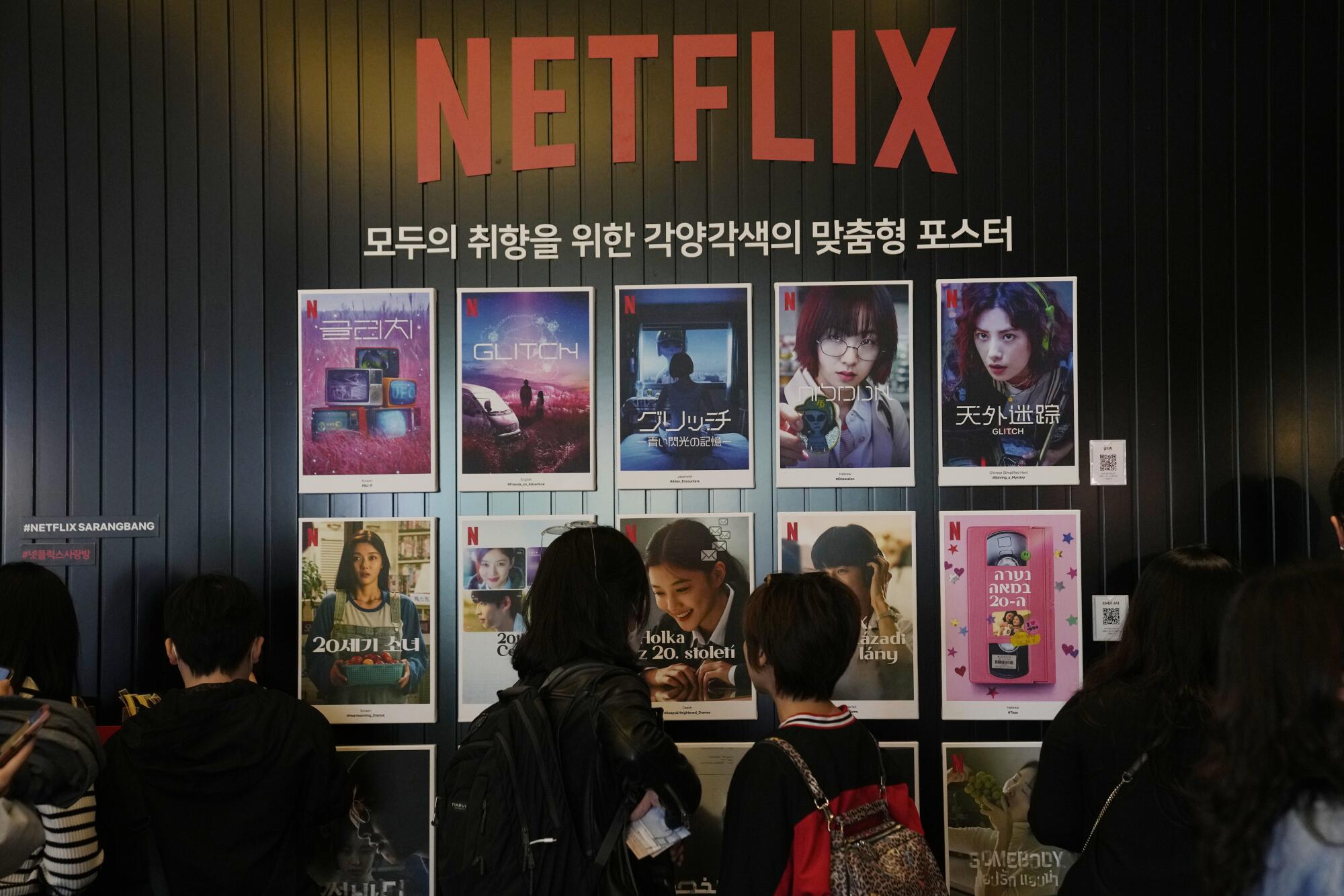 People walk past Netflix posters 