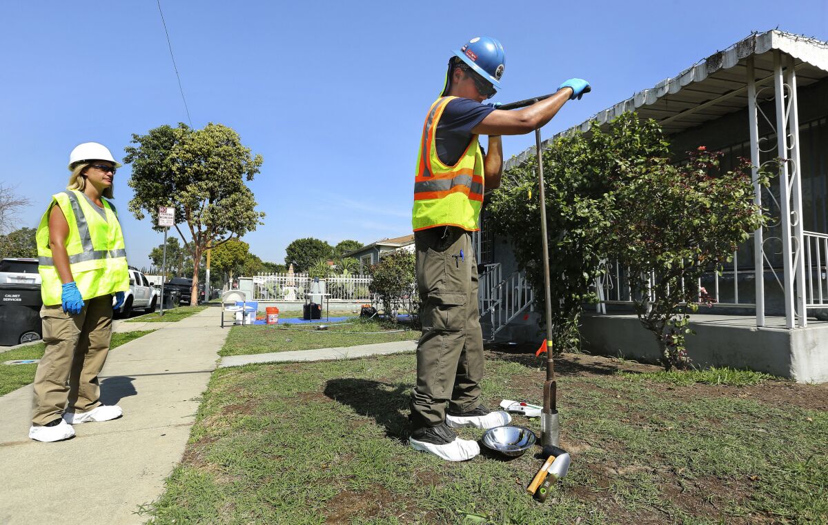 Environmental health specialists Jaime Jarrett, left, and Glen Van Eekout test the soil from the front yard of a home on Hepworth Avenue in the City of Commerce for possible lead contamination from the now-closed Exide battery plant on Feb. 29.