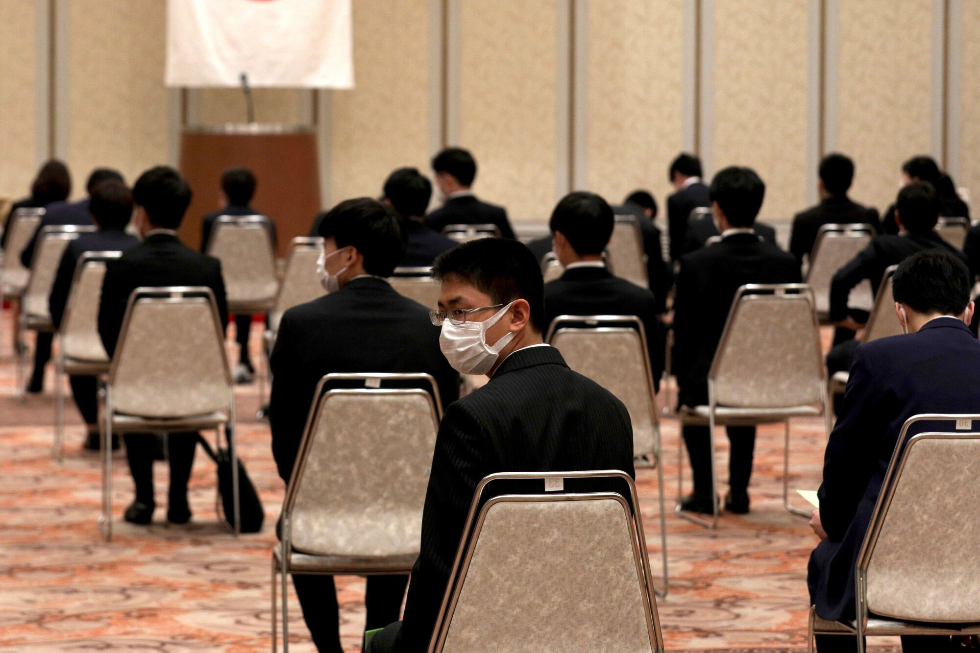 JAPAN: New employees wear face masks as they observe social distancing during an initiation ceremony at the Himeji Chamber of Commerce and Industry hall on Wednesday in Himeji, Japan.