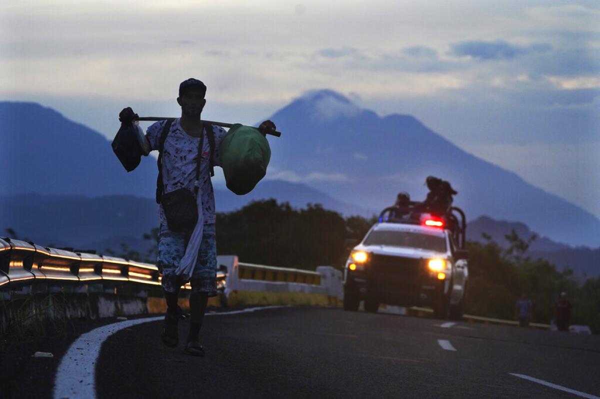 ARCHIVO - Un migrante camina por una carretera, 