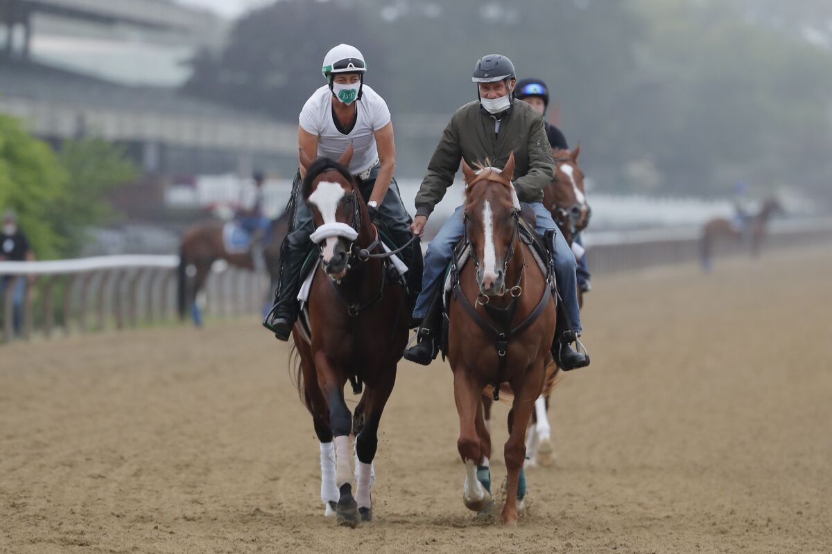 Robin Smullen on Tiz the Law, left, is led around the track by trainer Barclay Tagg in a workout at Belmont Park. 