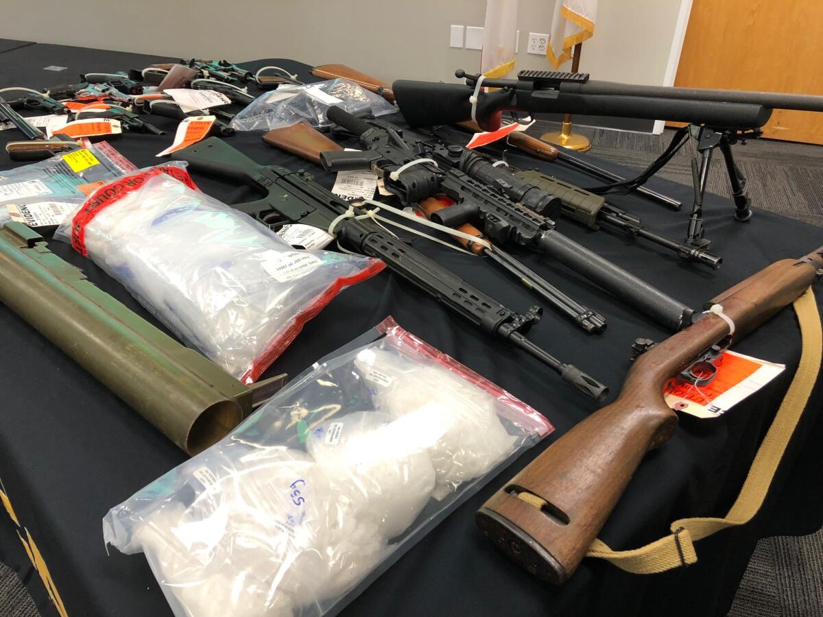 Several firearms and plastic bags of meth on a table
