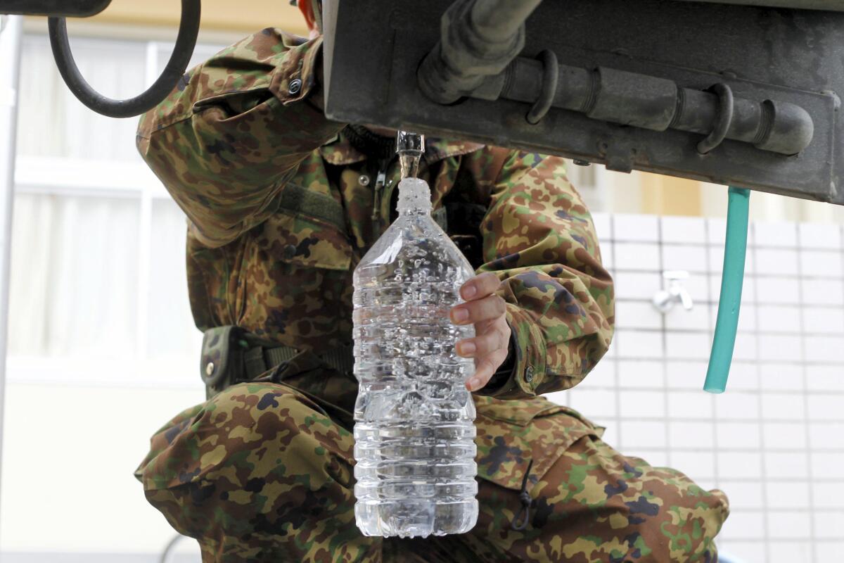 Un soldado rellena botellas de agua potable en un centro de evacuación en Rikuzentakata, en la prefectura de Iwate, Japón.