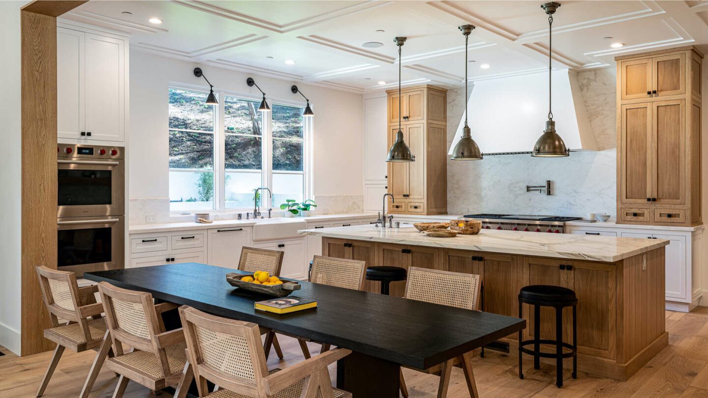 High coffered ceilings, a wood floor and a large marble-topped island in the kitchen.