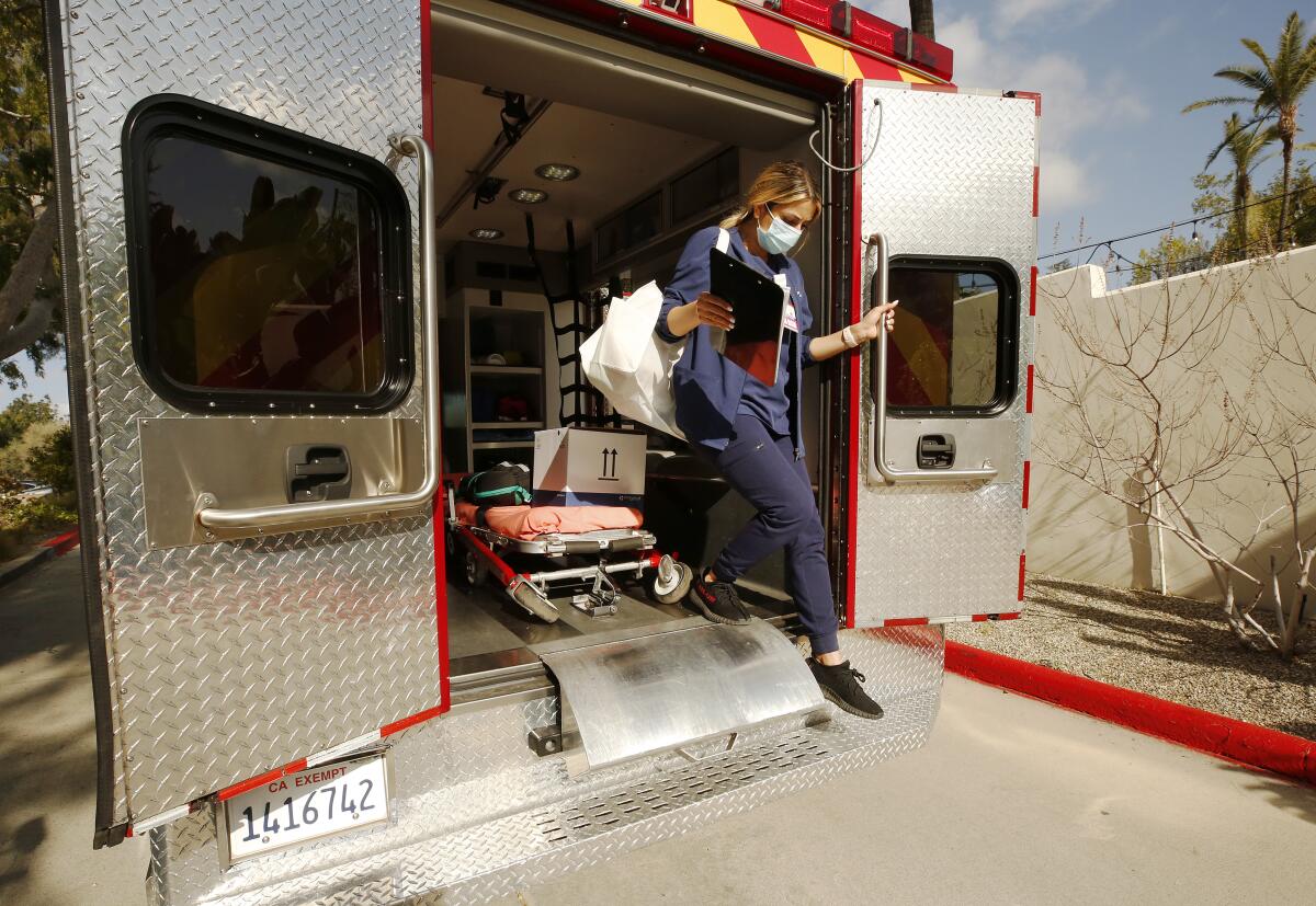 A nurse exits the back of an ambulance