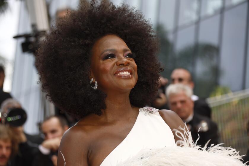 Viola Davis smiling in a white fuzzy dress and sparkly earrings.