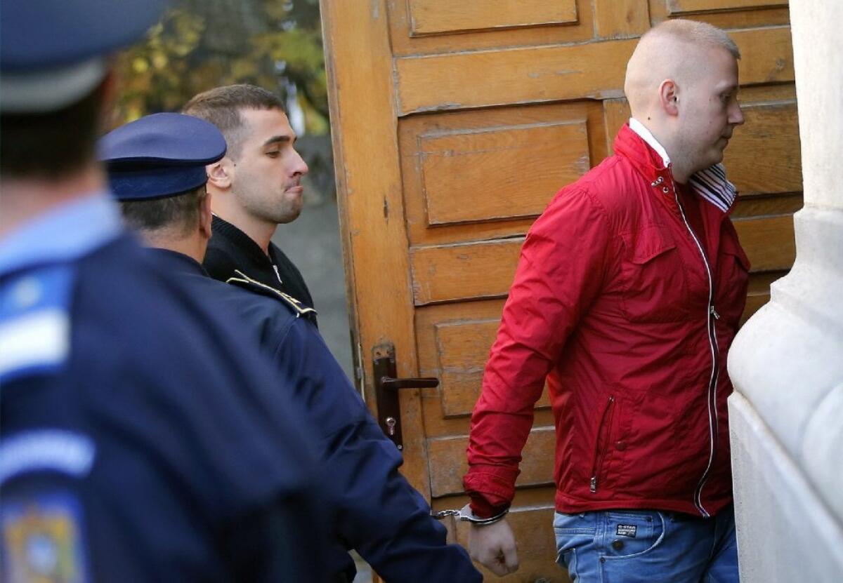 Art theft suspects Eugen Darie, right, and Radu Dogaru are escorted by police as they arrive handcuffed at a courthouse in Bucharest, Romania.