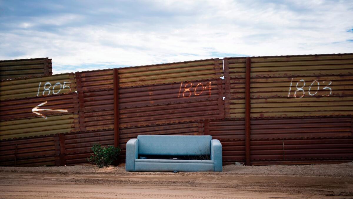 An abandoned sofa sits against the U.S.-Mexico border fence in Tecate, Calif.