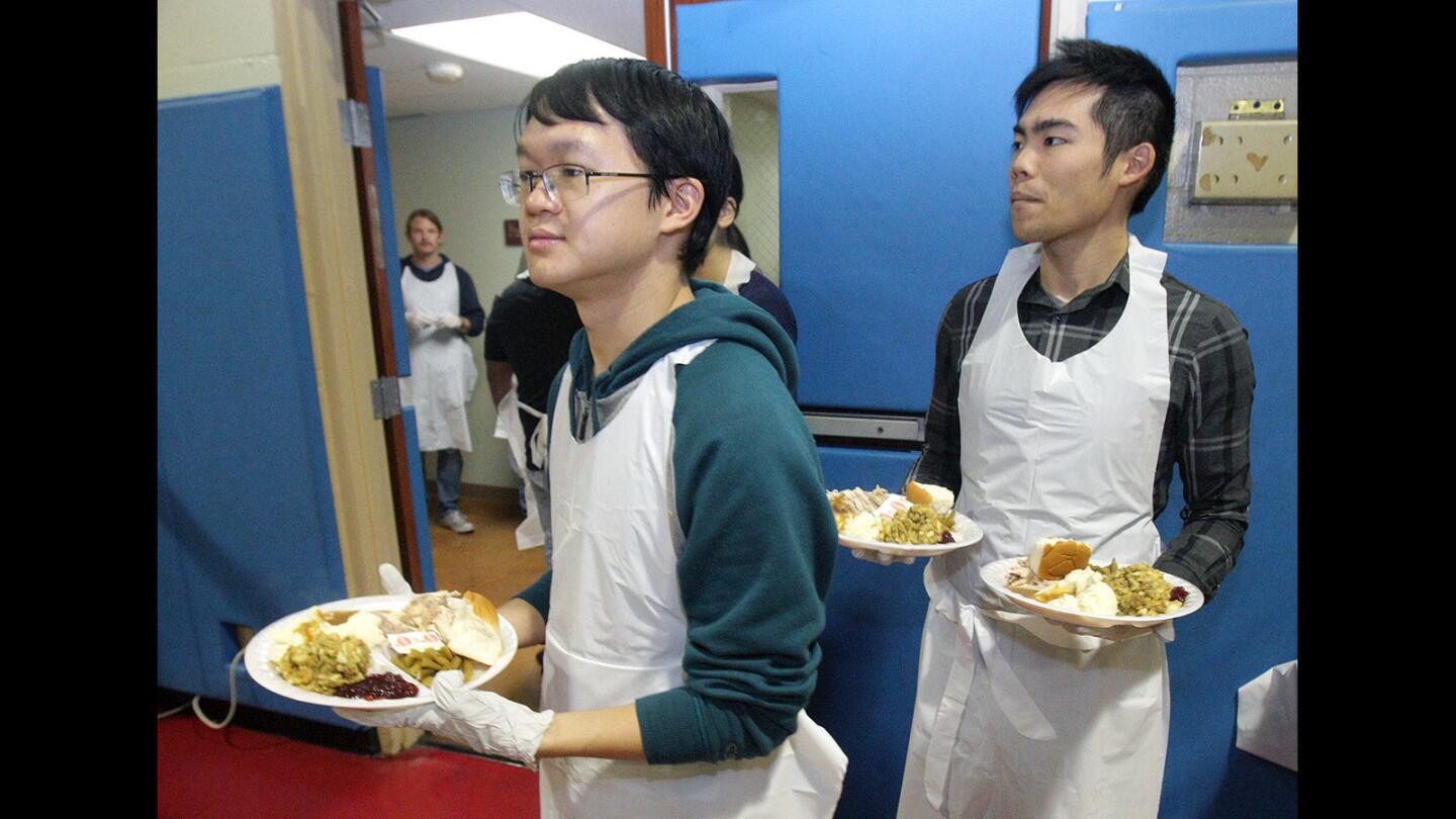 Caleb Wong, of Los Angeles, and Jeremy Wong, of Pasadena, wait for guests to be seated so they can serve them food at the Salvation Army Glendale Corps and Community Center Thanksgiving dinner in Glendale on Thursday, Nov. 26, 2015.