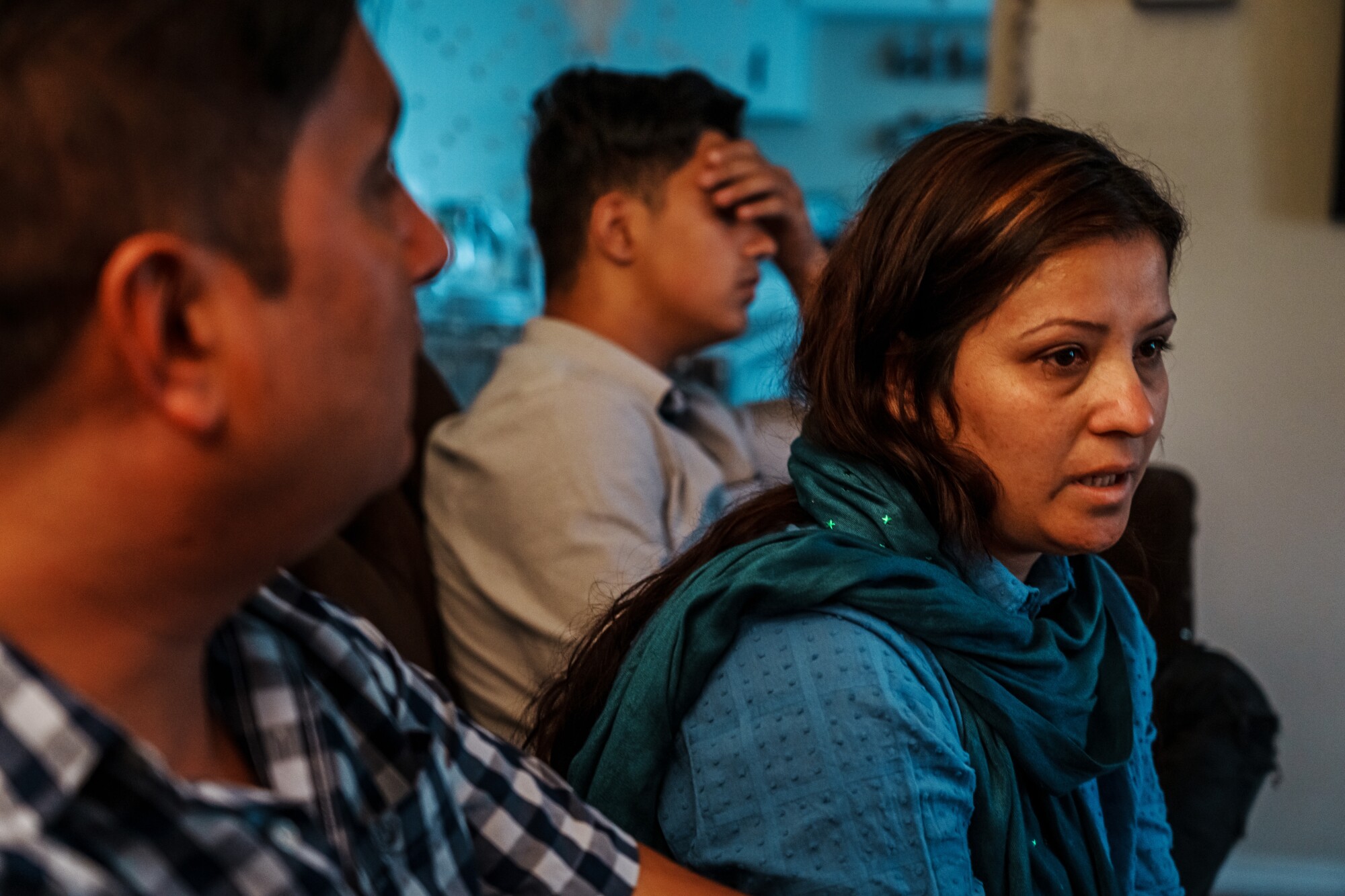 A year after the U.S. pullout from Afghanistan, refugees are still struggling to resettle 2 A woman dressed in blue, flanked by two men, speaks