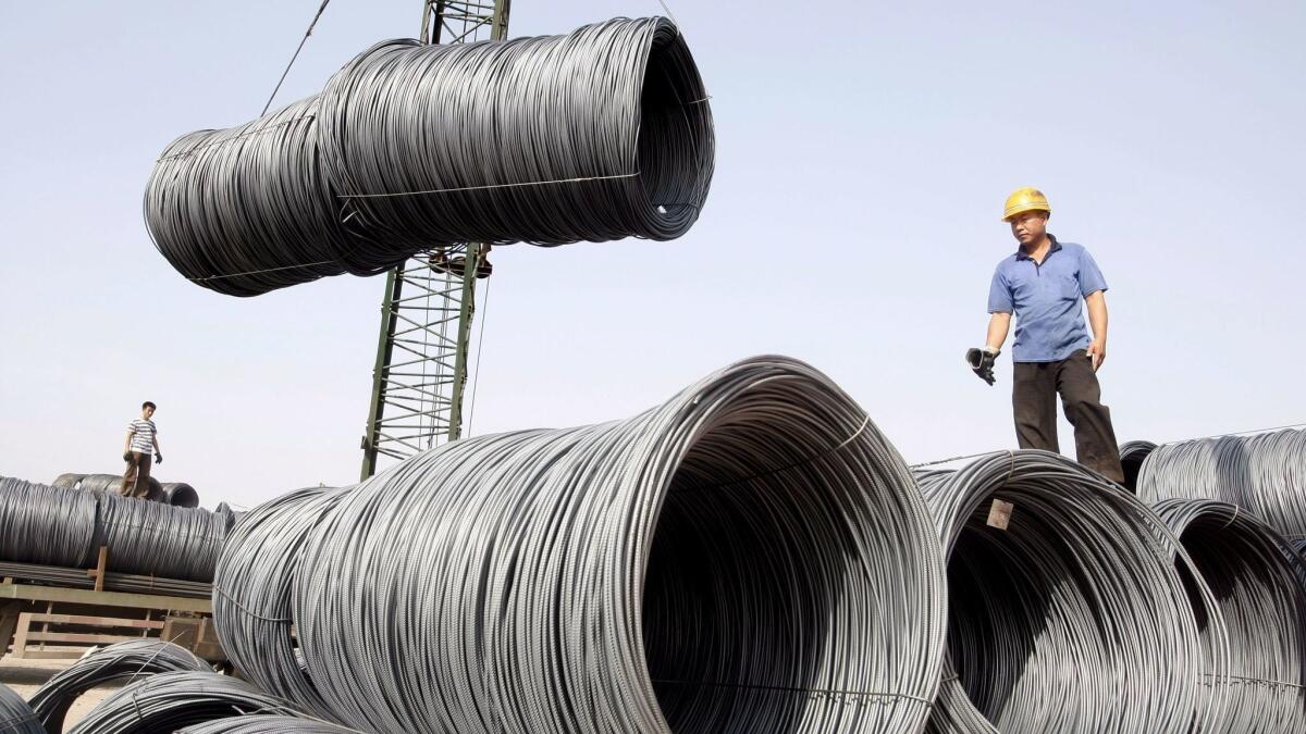 Workers transport steel cables at a steel yard in Beijing.