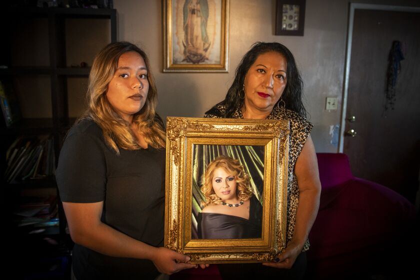 SANTA ANA, CALIF. -- SEPTEMBER 26, 2019: Melody, 18, left, and her grandmother, Herlinda Salcedo hold a portrait of their mother and daughter, murder victim Martha Anaya, who’s last known location was First Street and Grand Avenue, 6:26 p.m. in Santa Ana, Nov. 12, 2013. (Allen J. Schaben / Los Angeles Times)