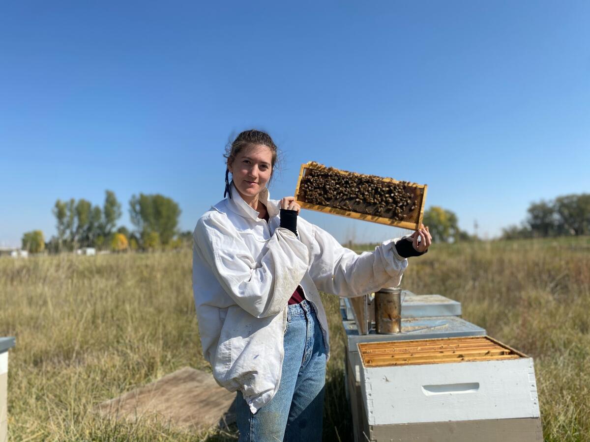 A woman standing by a beehive