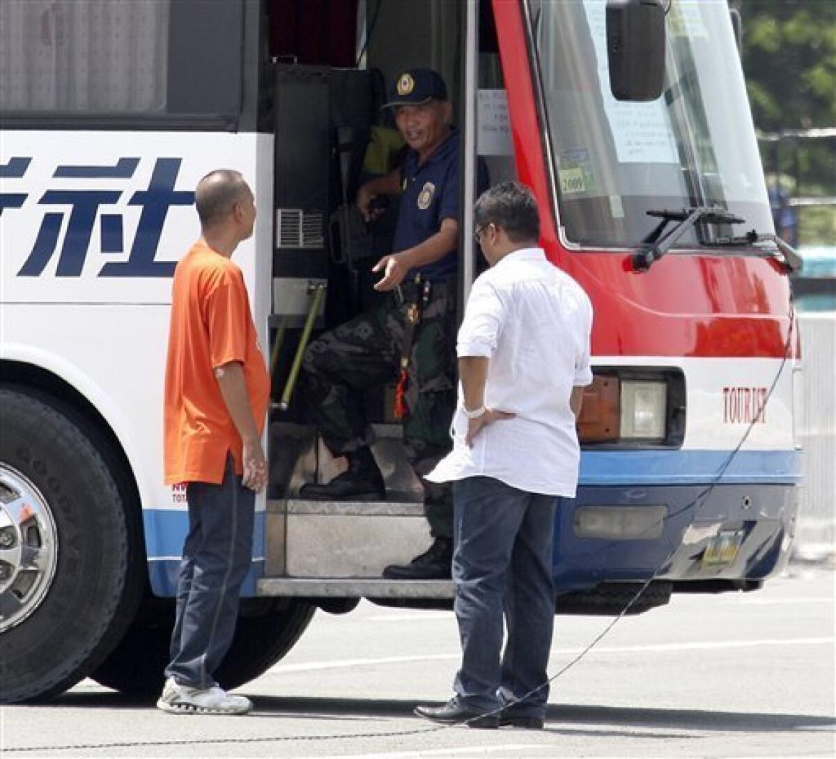 Police Senior Inspector Rolando Mendoza stands by the entrance of a tourist bus as negotiators talk to him during a standoff at Manila's Rizal Park Monday, Aug. 23, 2010 in Manila, Philippines. Mendoza, a dismissed policeman armed with automatic rifle, seized the bus in Manila Monday with 25 people aboard, mostly Hong Kong tourists in a bid to demand reinstatement, police said. (AP Photo/Bullit Marquez)