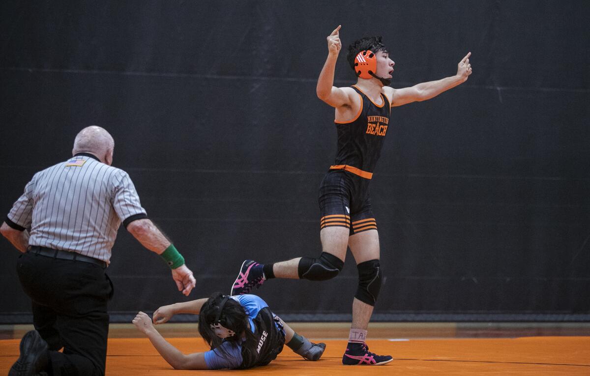 Huntington Beach's William Krcelic celebrates after pinning Corona del Mar's Wayne Muse in the 138-pound match of a Wave League opener on Wednesday in Huntington Beach.