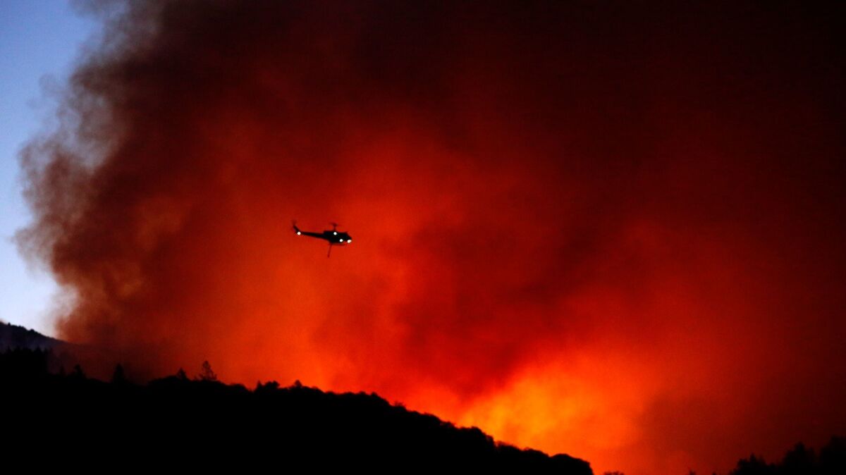 A helicopter prepares to drop water on a fire threatening the Oakmont community along Highway 12 in Santa Rosa, Calif., on Oct. 13.