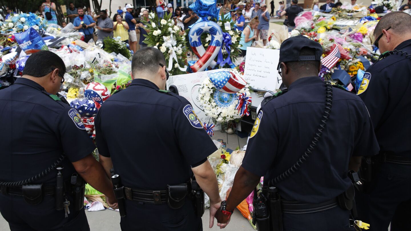 DART Police officers pray in front of the Dallas police headquarters on Saturday.