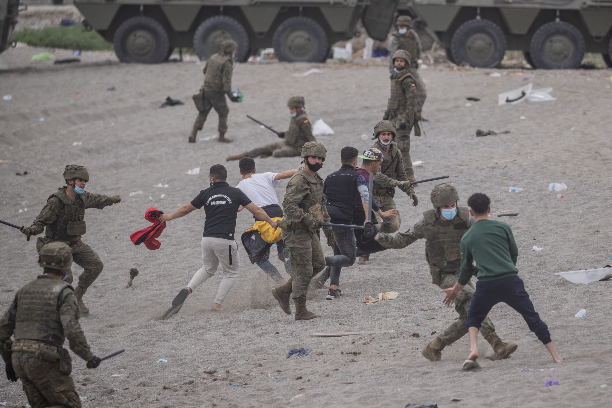 A group of soldiers fight with batons against five young male migrants on a beach