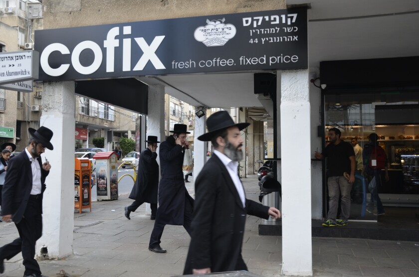 Ultra-Orthodox residents of Bnei Brak pass a new Cofix store on the main street.