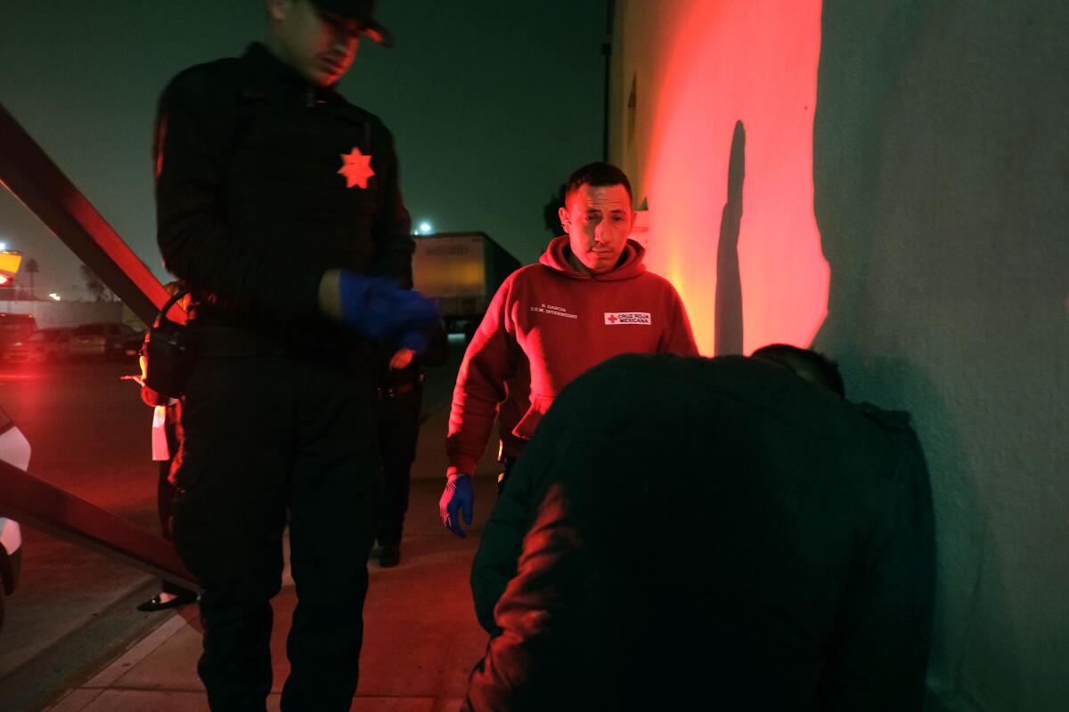 El paramédico de la Cruz Roja Mexicana Sergio García, en el centro, se prepara para atender a un hombre que tuvo un ataque el viernes en Tijuana.