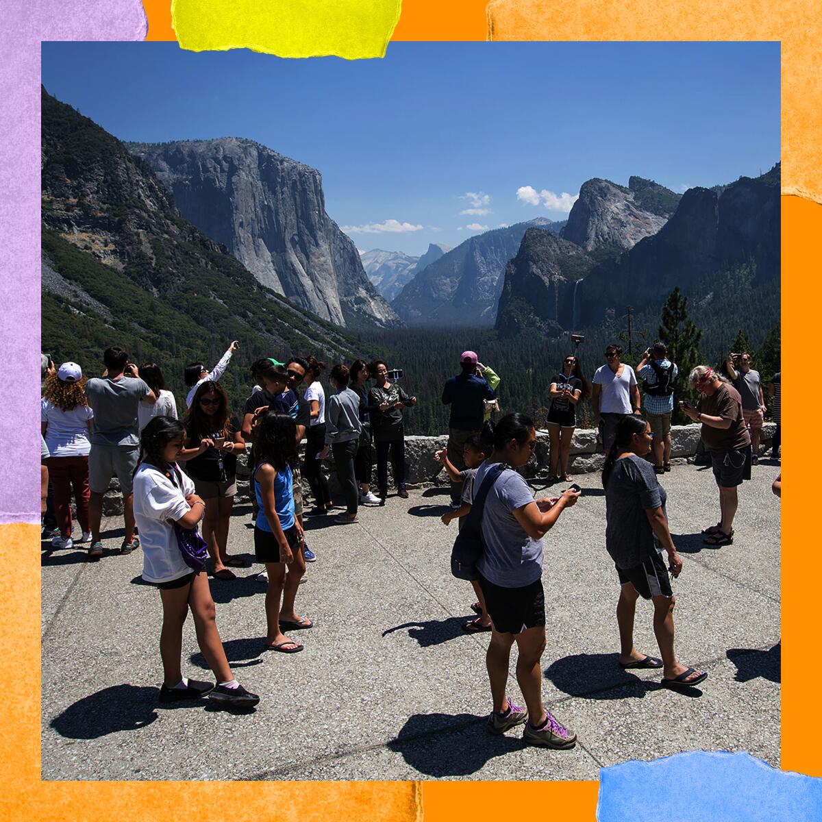 People stand in a paved area among mountain peaks.