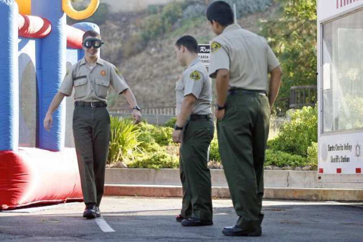 Los Angeles County Sheriff explorers Vicken Shahbazian, 15, from left, tries on DUI glasses as Sam Lopez, 19, and Richard Grandes, 19, watch Shahbazian walk in a straight line during an annual open house, which took place at Crescenta Valley's sheriff's station on Saturday.