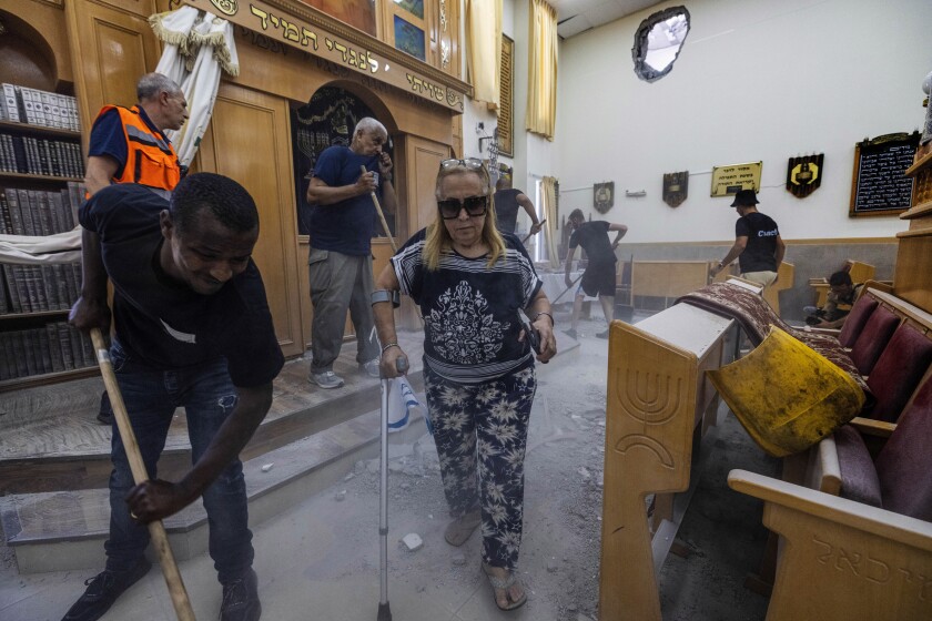 People clean debris from a damaged synagogue after it was hit by a rocket fired from the Gaza Strip, in Ashkelon, Israel, Sunday, May 16, 2021. (AP Photo/Tsafrir Abayov)