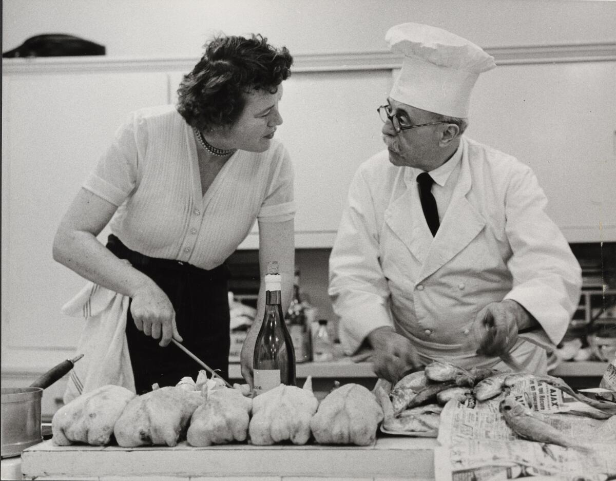 A black-and-white photograph of a woman and a man preparing chicken and fish.